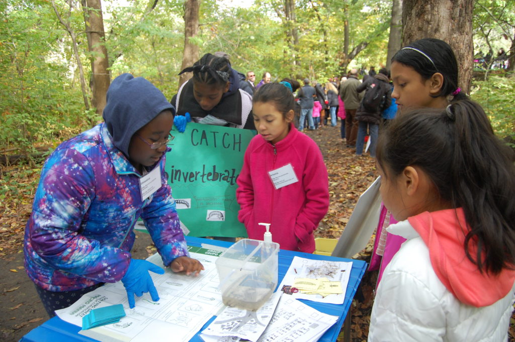 STUDENTS HUDDLE AROUND a table set up inside Bronx River Forest learning about the variety of macroinvertebrates found along the river. Photo courtesy Bronx Community Charter School