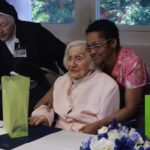 NURSE ROSEMARY BARRETT (right) embraces and gives a gift to 99-year-old Ada MacDonald during the Centennial Celebration at the St. Patrick’s Home on June 19. In the background is Sr. Kevin Patricia Lynch. Photo by Sophia Ebanks.